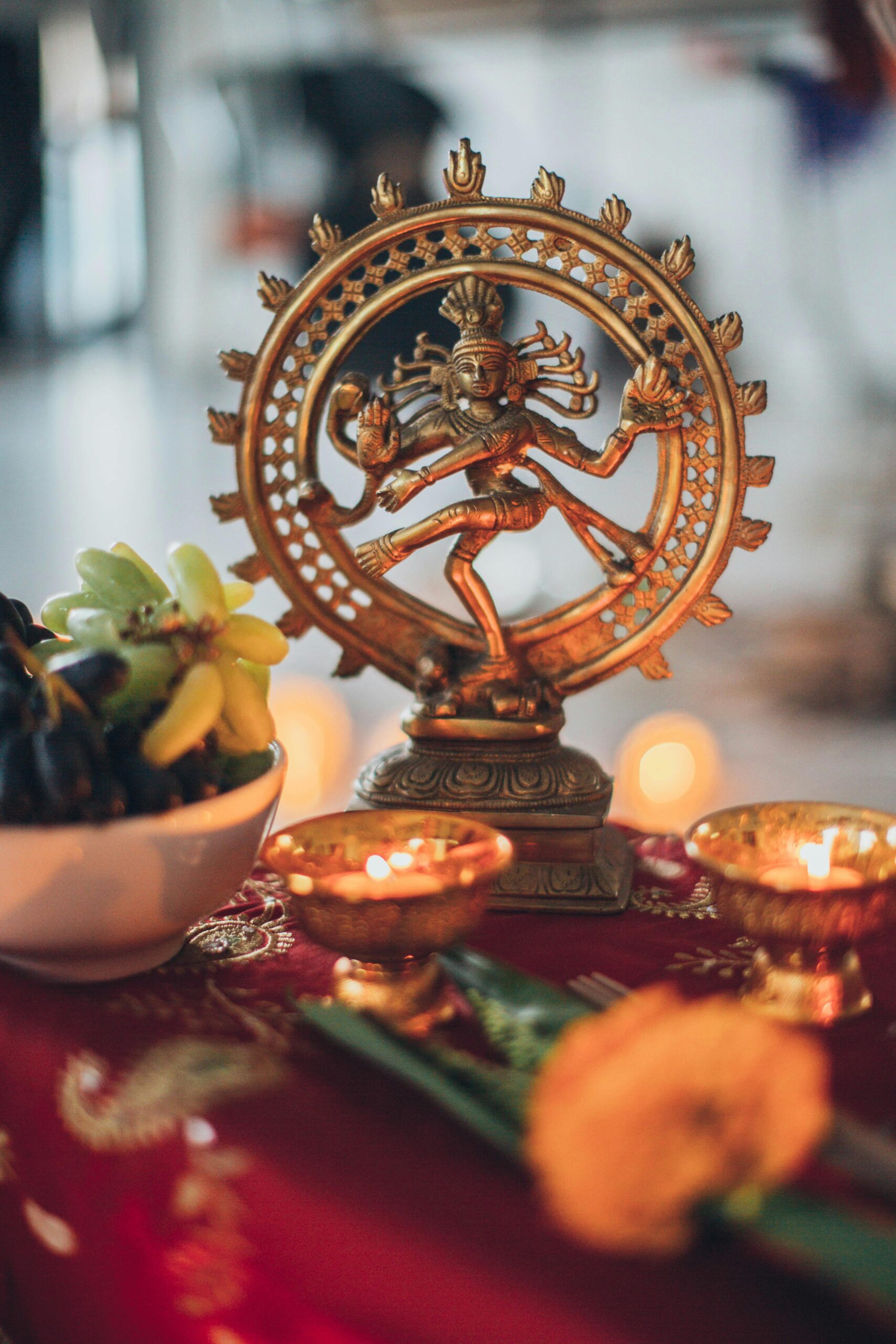 Intricate Shiva Nataraja statue surrounded by traditional offerings and candles on a vibrant altar.